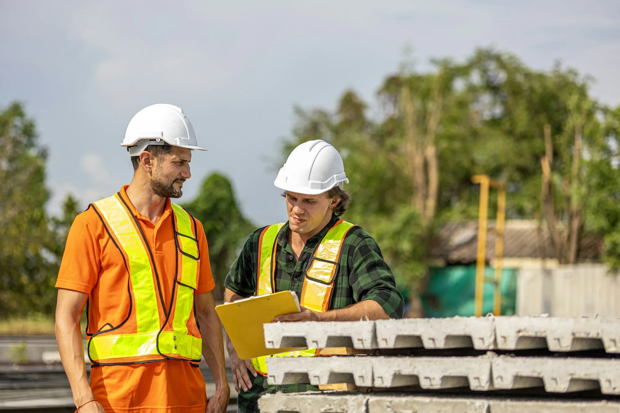 Two electricians reviewing a job plan on a clipboard outdoors