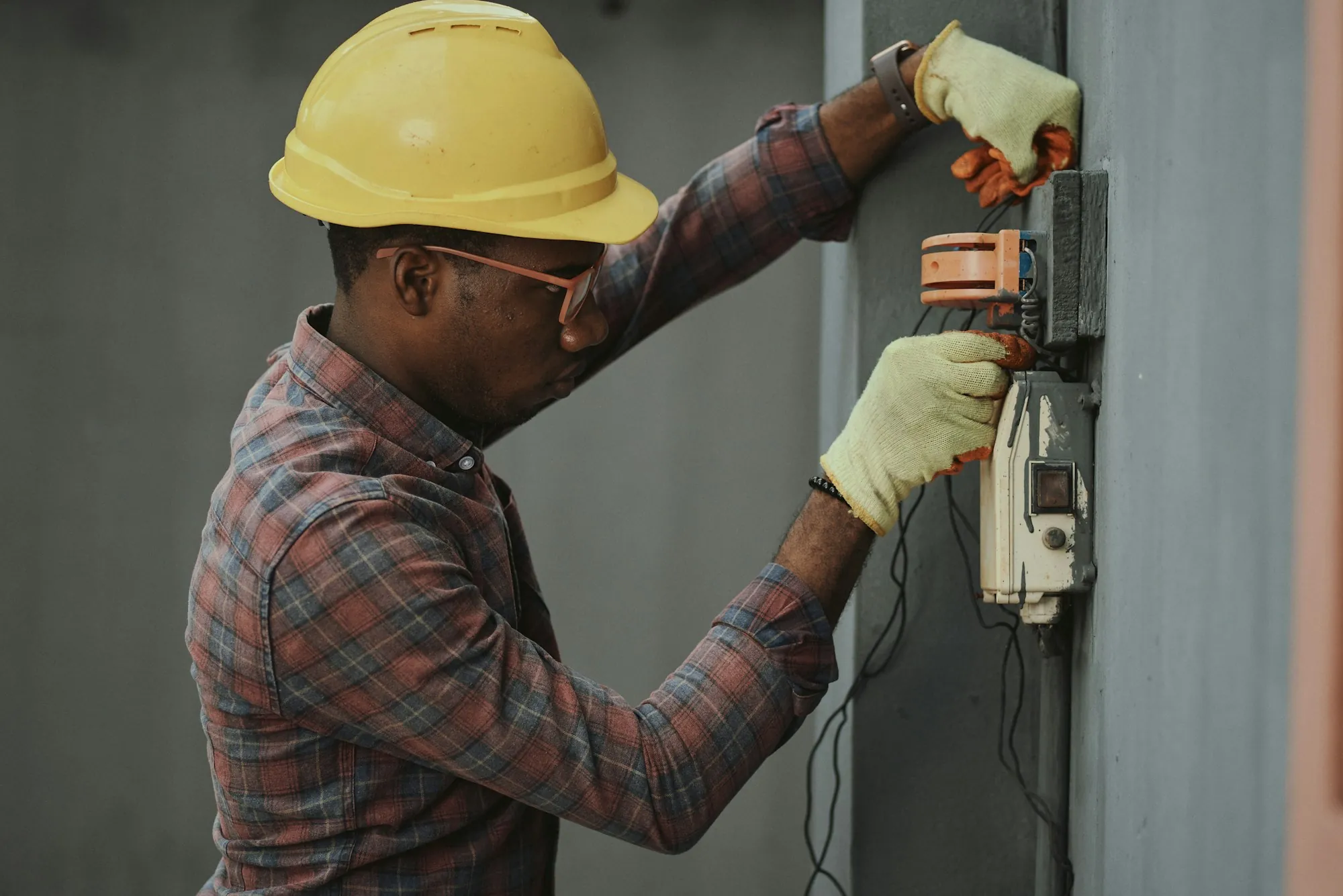 Electrician in a hard hat working inside a home electrical panel