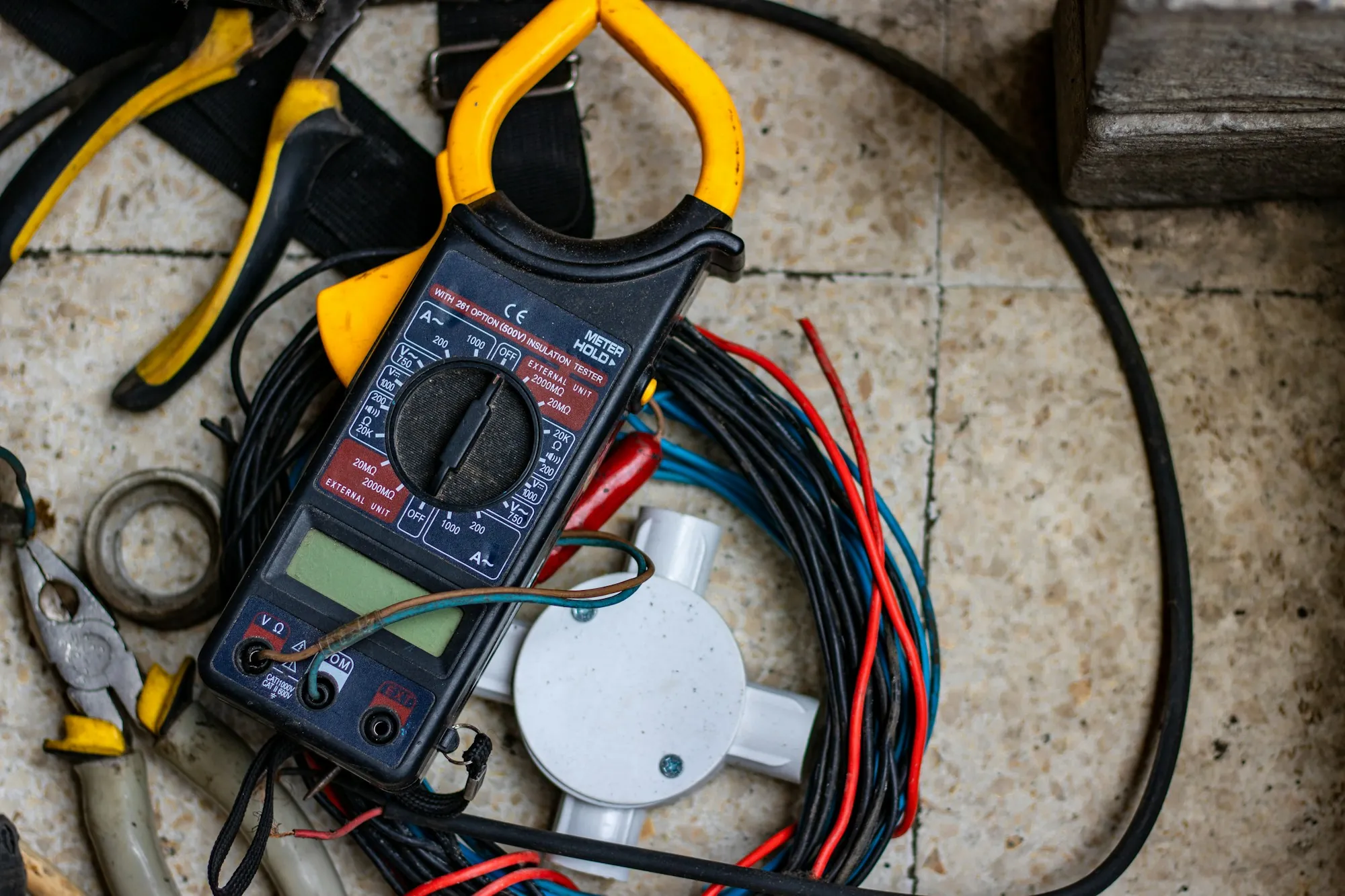Digital multimeter and test leads laid on electrical cable