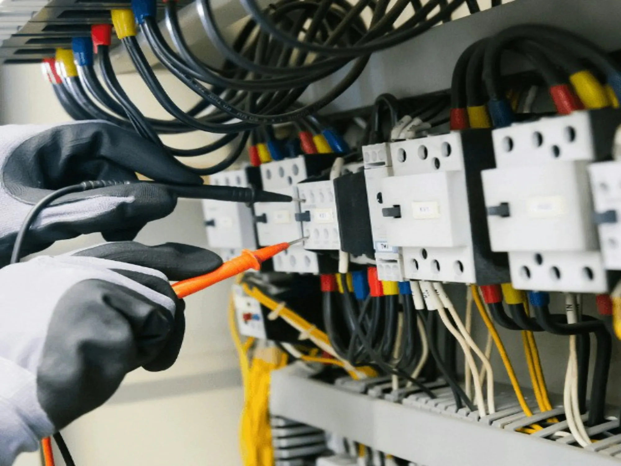 Electrician testing a live panel with a probe and insulated gloves