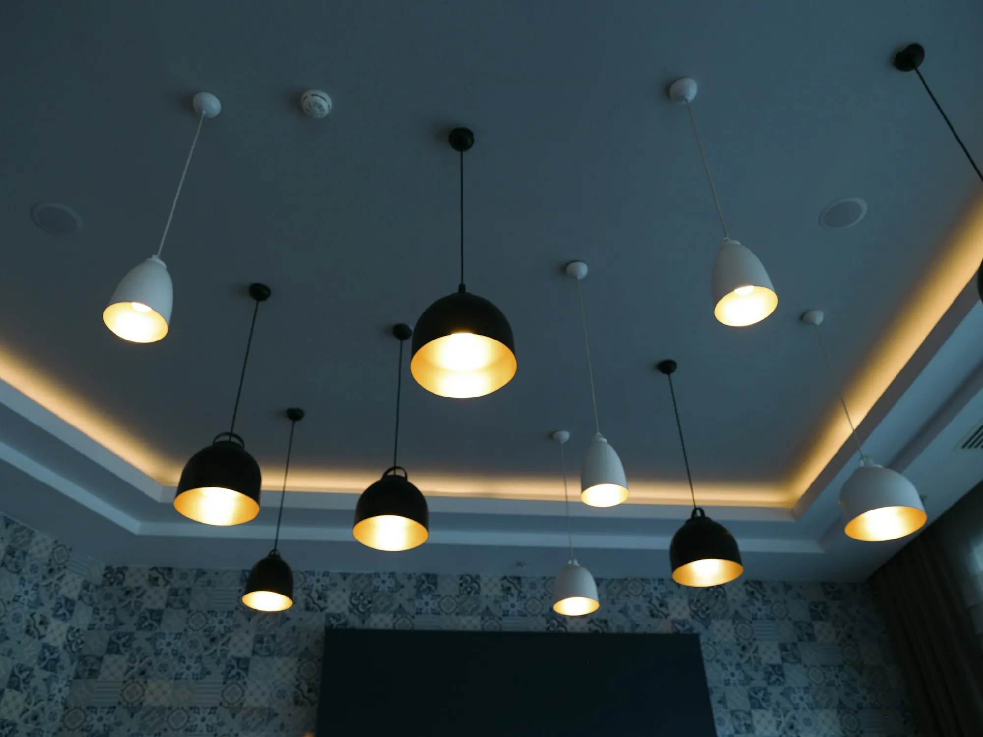 Row of black pendant lights hanging over a dark kitchen ceiling