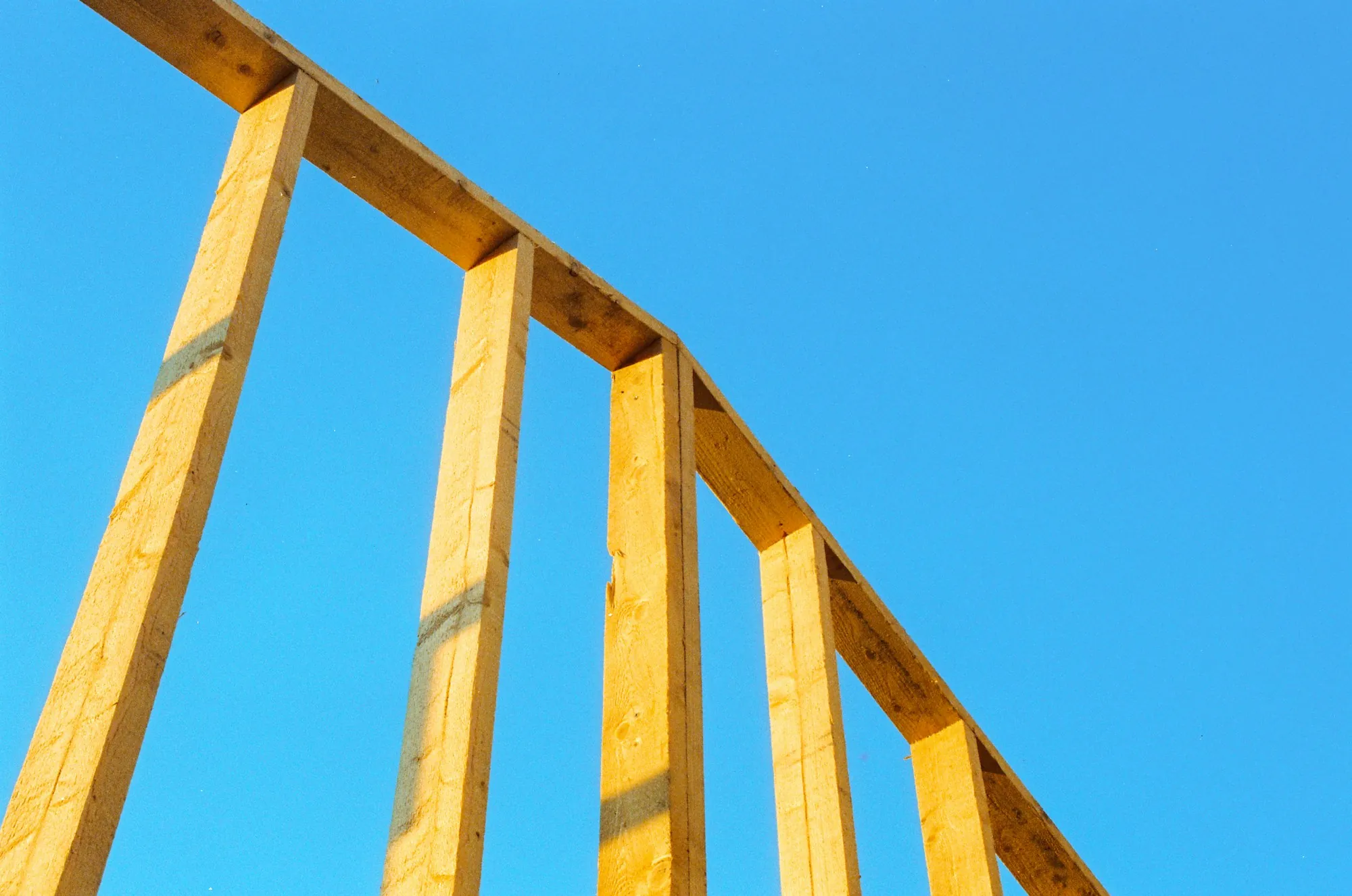 Timber wall framing of a new house against a blue sky