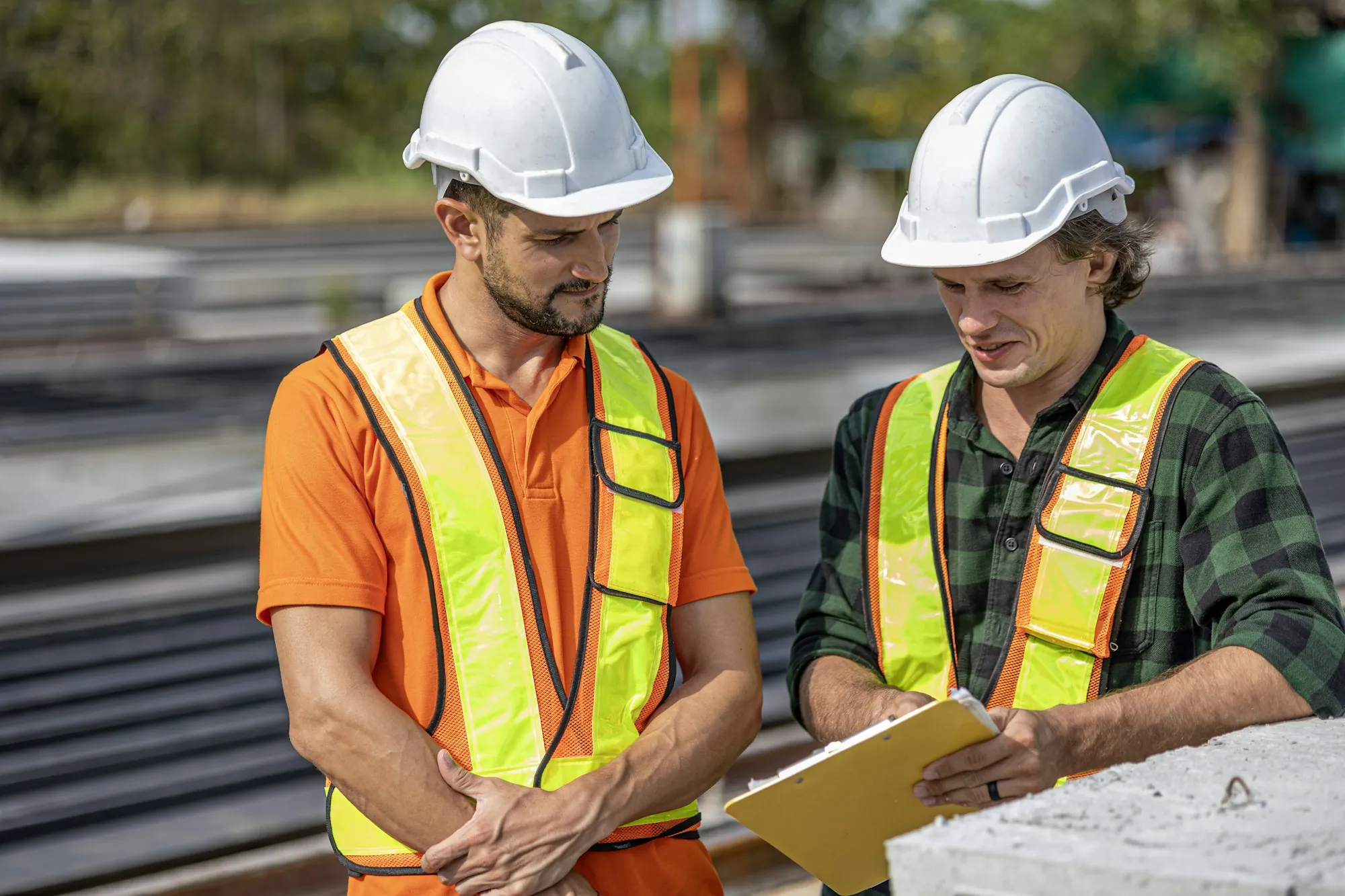 Two electricians in safety vests talking through a job on site
